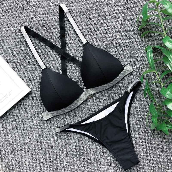 Czarne bikini z błyszczącymi paskami ułożone płasko na powierzchni