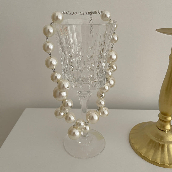 Detal eleganckiej kolii z pereł, ukazujący ich blask i precyzyjne wykonanie. Wysoka jakość.