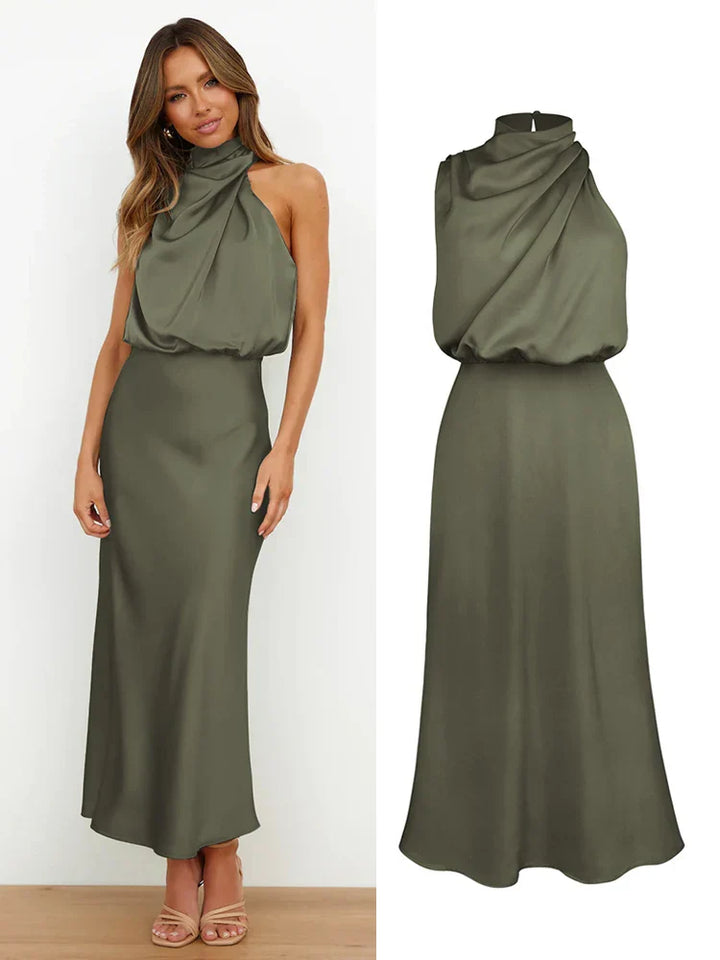 Modelka prezentuje sukienkę midi z asymetrycznym dekoltem halter. Elegancka satynowa stylizacja.