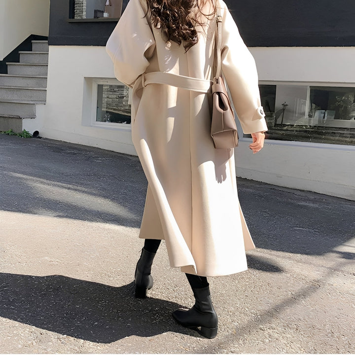 Stylowy beżowy płaszcz damski, długi i elegancki. Idealny na jesienne dni, modna odzież przejściowa.