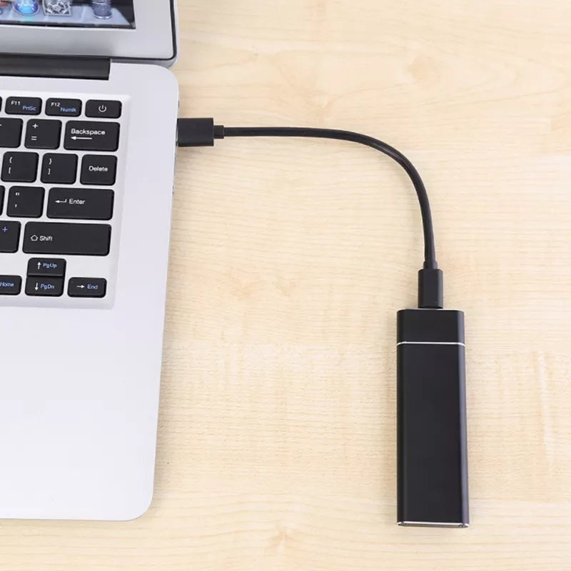 Czarny zewnętrzny dysk SSD leżący na biurku obok akcesoriów komputerowych