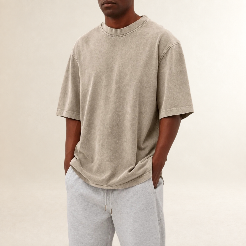 Mężczyzna w beżowym t-shircie relaxed fit z krótkim rękawem i szarych spodniach dresowych