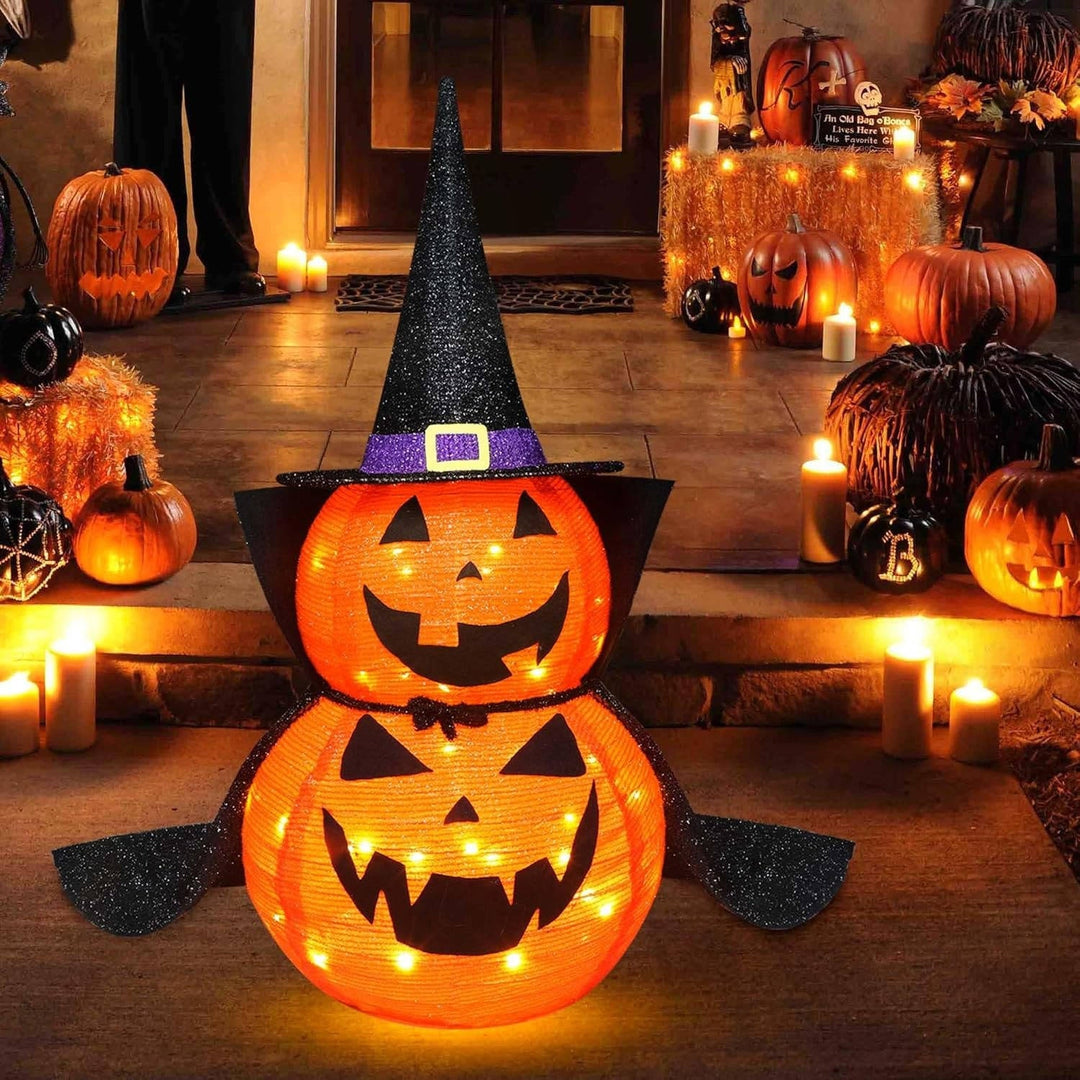 Oświetlona dynia halloweenowa z czapką czarodzieja stojąca na werandzie