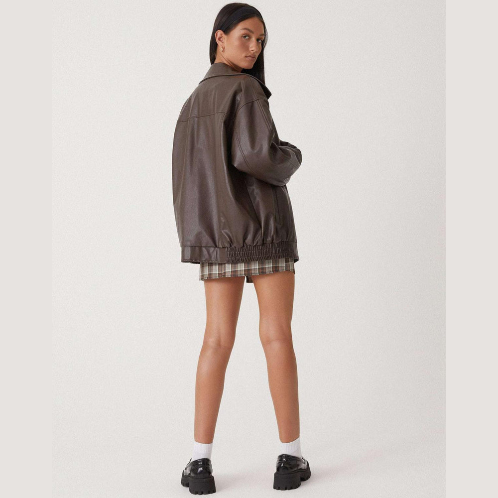 Kobieta w brązowej kurtce oversize tyłem
