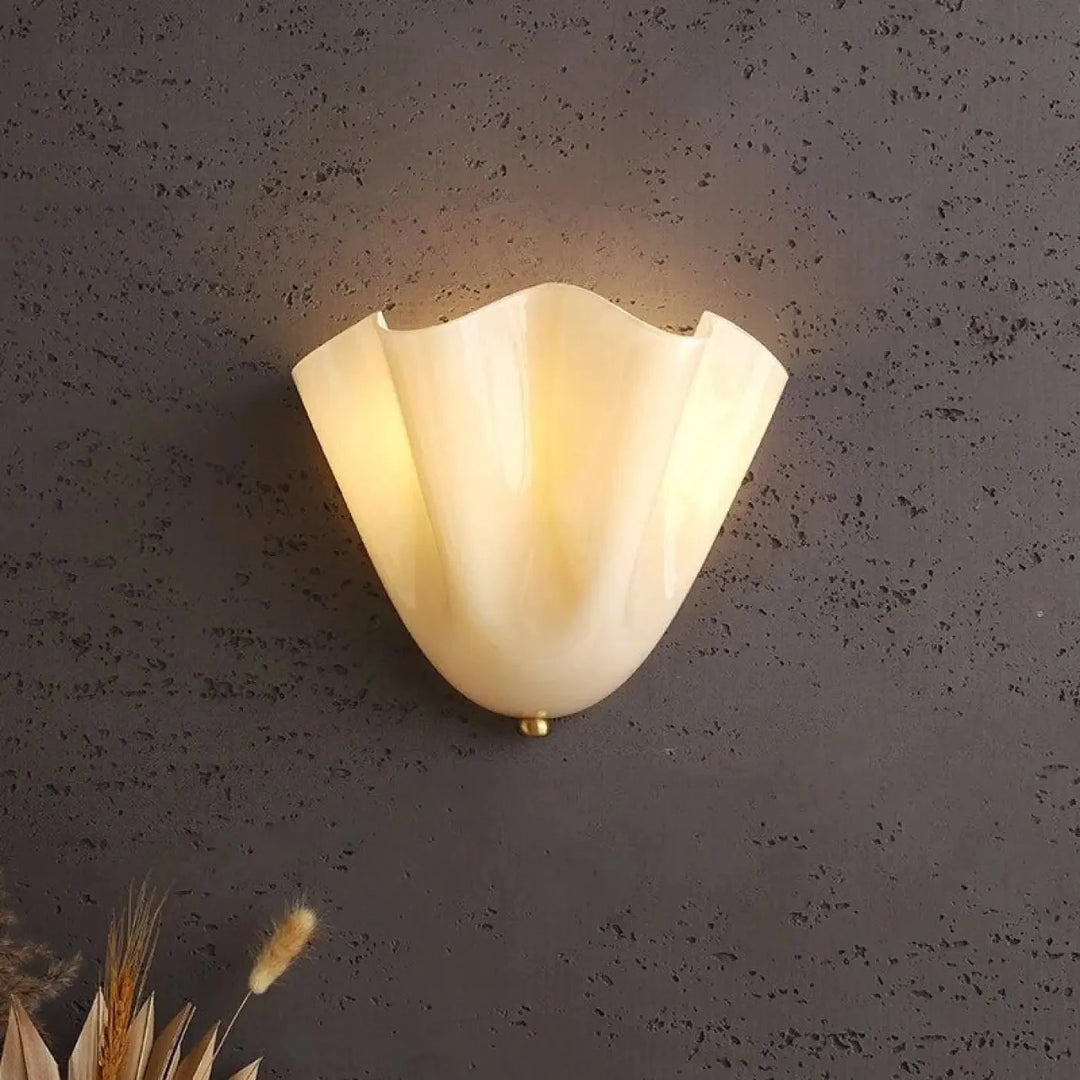 Beżowy kinkiet art deco ze szklanym kloszem w kształcie muszli na szarej ścianie