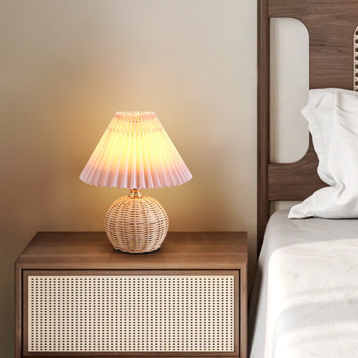 Skandynawska lampa stołowa LED, rattanowa podstawa, beżowy plisowany abażur, subtelne oświetlenie.