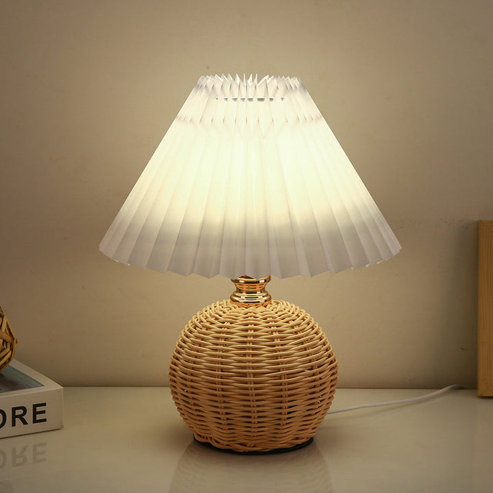 Elegancka lampa stołowa LED z abażurem plisowanym i podstawą z rattanu, idealna do sypialni.