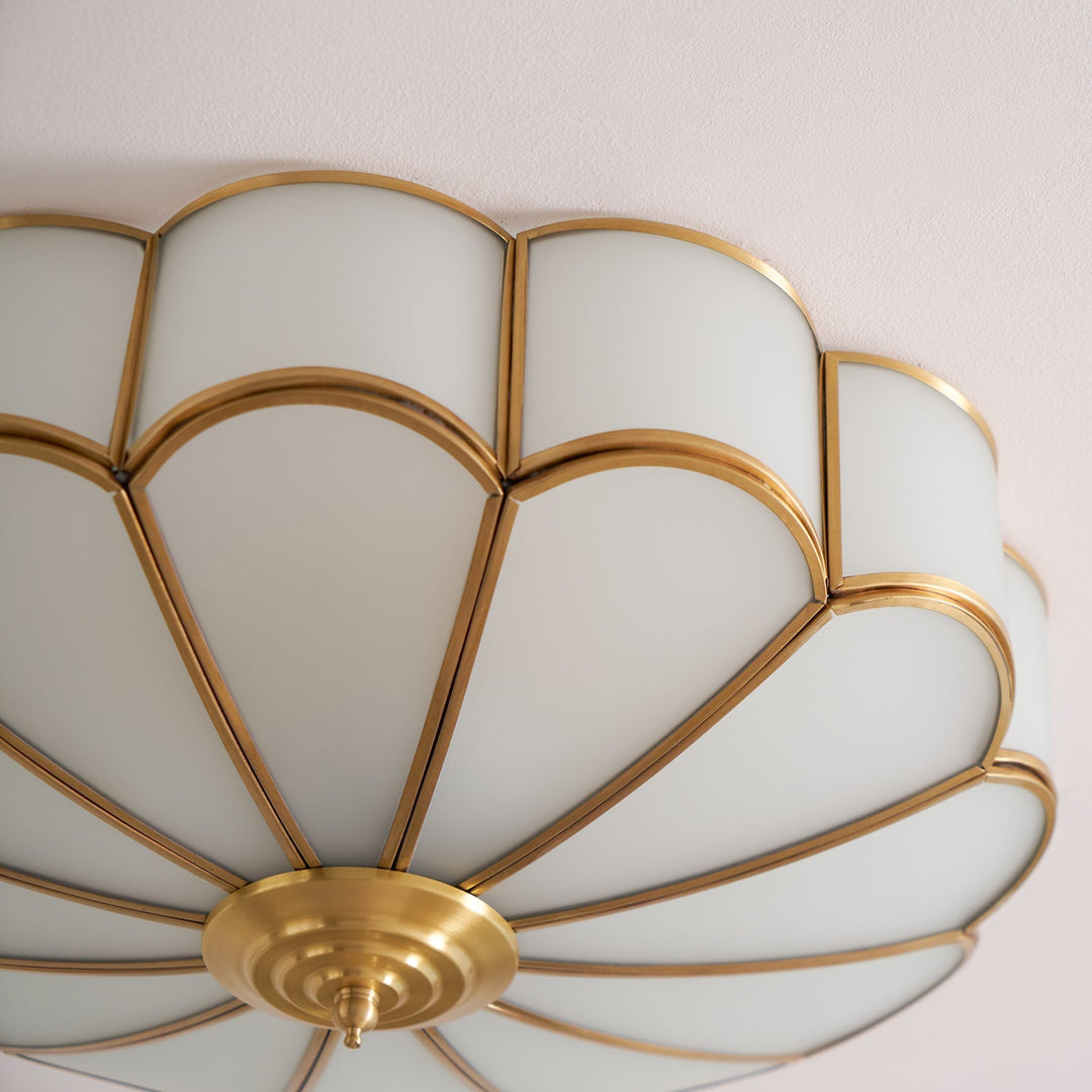 Designerska lampa wpuszczana, biała z mosiężnym wzorem kwiatowym, widok z boku.
