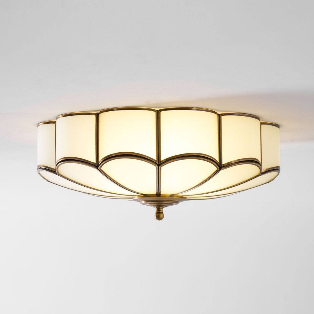Stylowa lampa wpuszczana, biała oprawa z mosiężnymi kwiatami, nowoczesny wygląd.