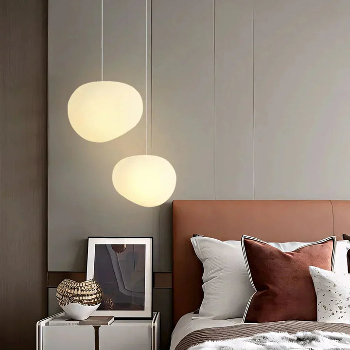 Lampa wisząca z kloszami w organicznym kształcie kamyków. Matowe szkło rozprasza światło w salonie.
