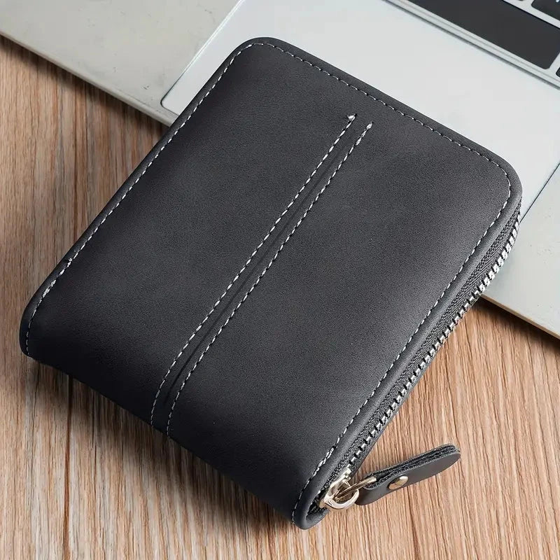 Elegancki czarny portfel męski prezentowany na tle laptopa