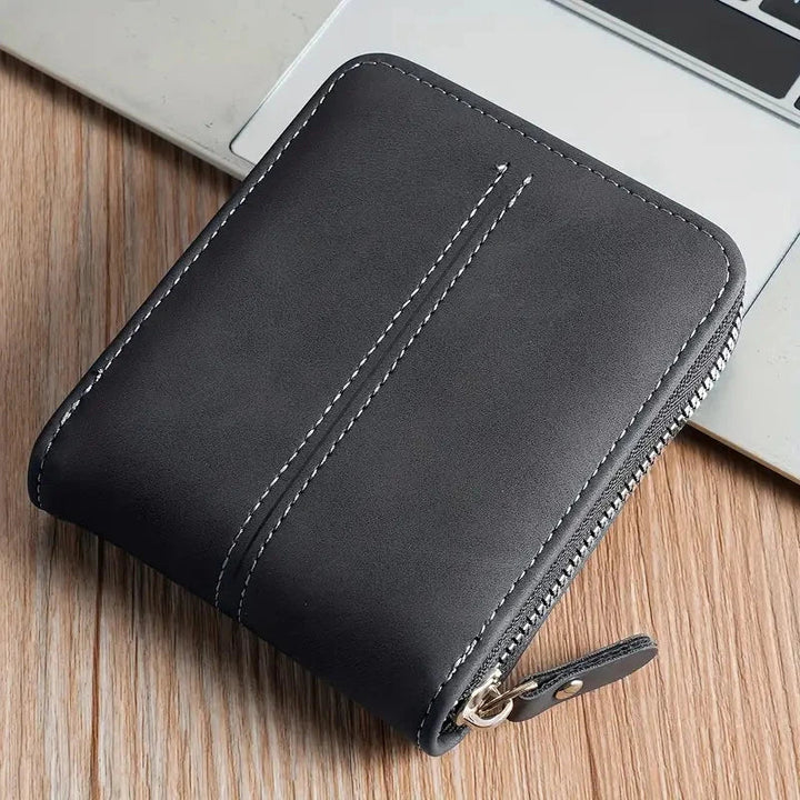 Elegancki czarny portfel męski prezentowany na tle laptopa