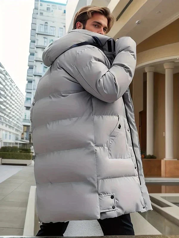 Mężczyzna prezentujący długą pikowaną kurtkę zimową. Modna ocieplana parka z kapturem.