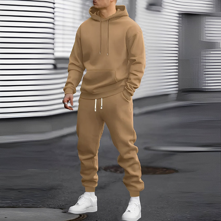 Mężczyzna w modnym dresie z kapturem. Komplet męski, bluza i spodnie dresowe. Idealny na relaks lub sport.