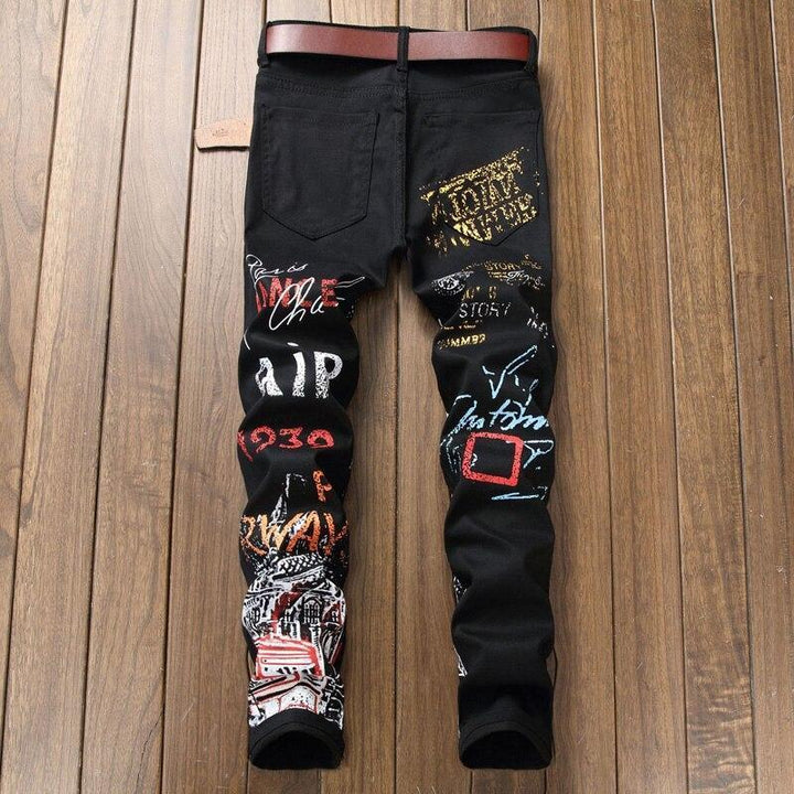 Modne męskie jeansy slim fit z unikalnymi nadrukami. Spodnie łączą czarne tło z białymi wzorami, podkreślając streetwearowy styl.