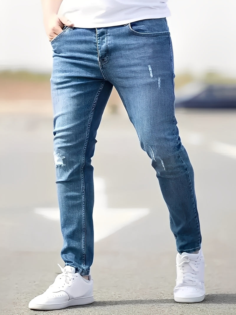 Ciemne męskie jeansy skinny z przetarciami na kolanach. Modne, wygodne spodnie denim dla mężczyzn.