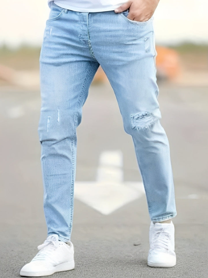Męskie modne skinny jeansy z efektem przetarć. Komfortowe spodnie denim o miejskim kroju dla mężczyzn.