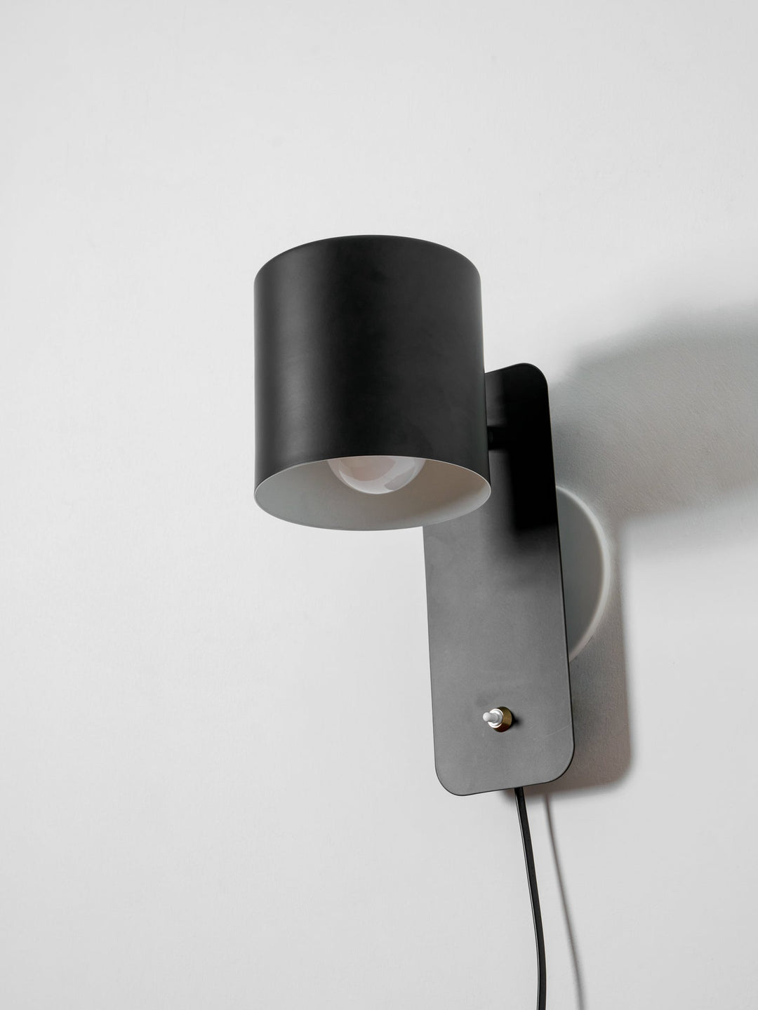 Czarna lampa ścienna obrotowa, do sypialni, nowoczesna i funkcjonalna.