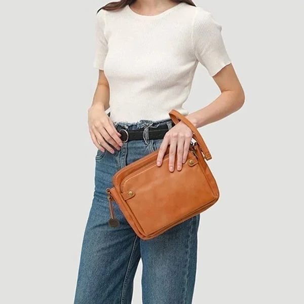 Kobieta trzymająca w dłoniach elegancką brązową kopertówkę