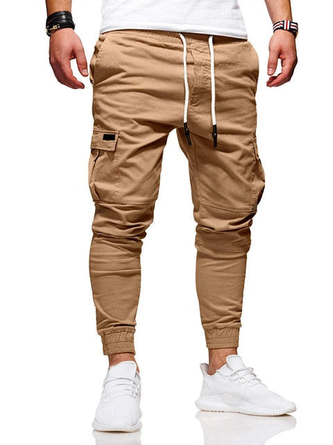 Mężczyzna w beżowych spodniach jogger cargo z kieszeniami i białymi sneakersami