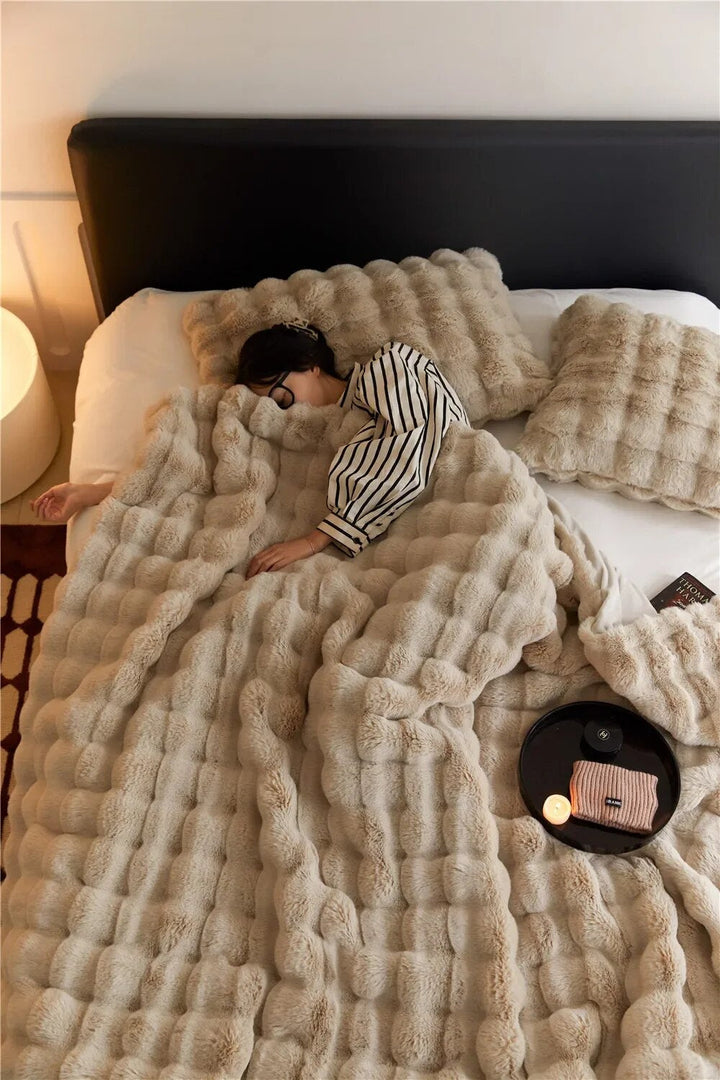 Puszysty koc WarmWool w neutralnym kolorze, idealny na chłodne wieczory, zapewniający ciepło i komfort w domu.
