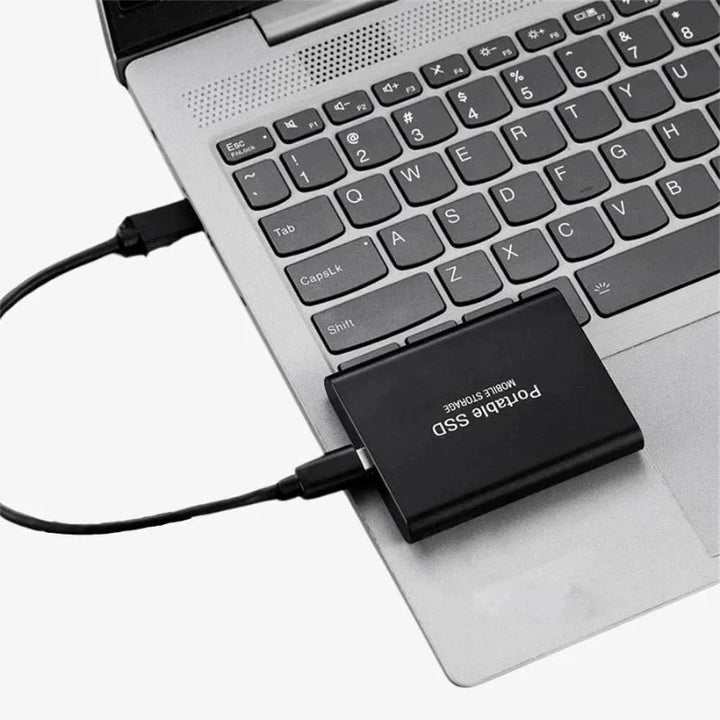 Czarny przenośny dysk SSD podłączony do nowoczesnego laptopa