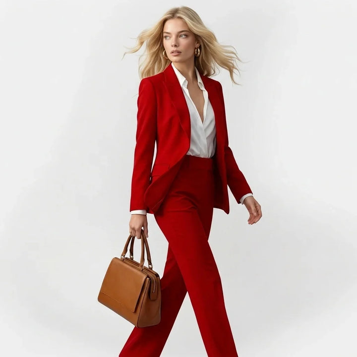 Modelka w czerwonym dwuczęściowym garniturze biznesowym z eleganckim żakietem i torebką