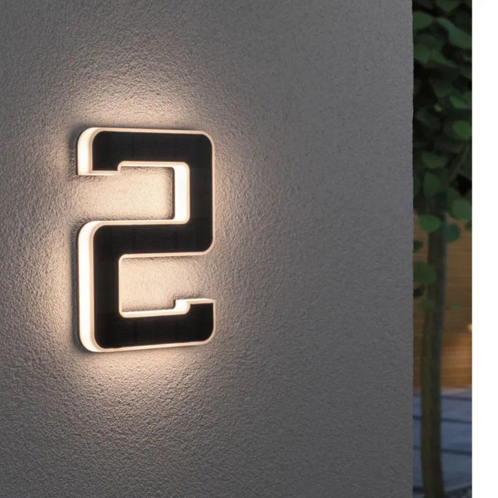 Solarna lampa elewacyjna z cyfrą dwa świecąca ciepłym światłem