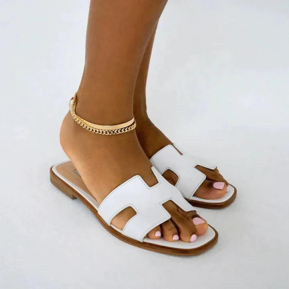 Modelka prezentująca białe modne klapki na stopach