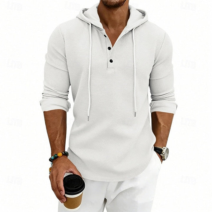 Mężczyzna w białej bluzie z kapturem trzymający kubek